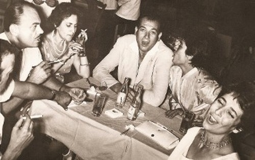 Στο κέντρο «Μυρτιά», ο ποιητής Δημήτρης Χριστοδούλου, η Ειρήνη Παππά, η Αλέκα Παΐζη και ο Τάσος Λειβαδίτης, με γυρισμένη την πλάτη, τραγουδούν τον «Καημό» (Ιούλης 1951