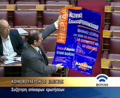 Ο Ορ. Κολοζώφ ενώ δείχνει στη Βουλή την αφίσα της ΔΑΠ που διαφήμιζε την παροχή πιστοποιητικών κατάρτισης στο ΤΕΙ
