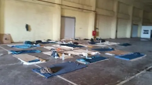 Σε μια κουβέρτα πάνω σε ένα χαρτόκουτο κοιμούνται πρόσφυγες και μετανάστες, στην παλιά αποθήκη όπου διαμένουν στο Ρέθυμνο