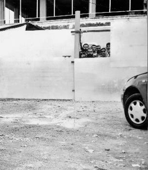 Στη φωτογραφία βλέπουμε τους πρόσφυγες να προσπαθούν να αντικρίσουν τον έξω κόσμο. Εναν κόσμο που τον φαντάστηκαν καλύτερο, αλλά το μόνο που τους επιφύλαξε ήταν μια τσίγκινη παράγκα με λύματα...