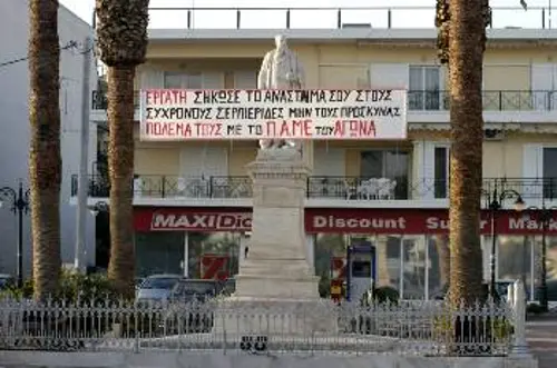 Το πανό, μπροστά απ' το άγαλμα του Σερπιέρι, καλεί: «Εργάτη, σήκωσε το ανάστημά σου στους σύγχρονες Σερπιέριδες. Μην τους προσκυνάς - Πολέμα τους με το ΠΑΜΕ του αγώνα»...