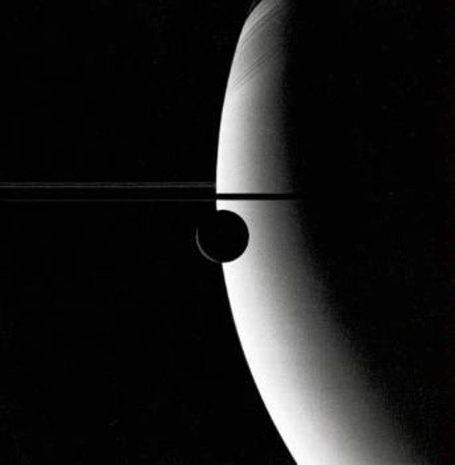 Η διαμέτρου 720 χιλιομέτρων Ρέα, είναι ο δεύτερος μεγαλύτερος δορυφόρος του Κρόνου. Στη φωτογραφία φαίνεται να αιωρείται λίγο πιο κάτω από τους δακτυλίους, που εμφανίζονται σχεδόν από το πλάι, αναδεικνύοντας τη λεπτότητα της δομής τους