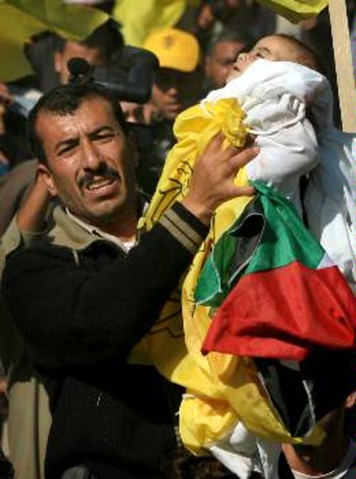 Ο δυστυχής πατέρας κρατάει στα χέρια του, τυλιγμένη στο σάβανο και την παλαιστινιακή σημεία, την ενός χρόνου κορούλα του Μάραμ, στη χτεσινή μαζική κηδεία - διαδήλωση στη Γάζα