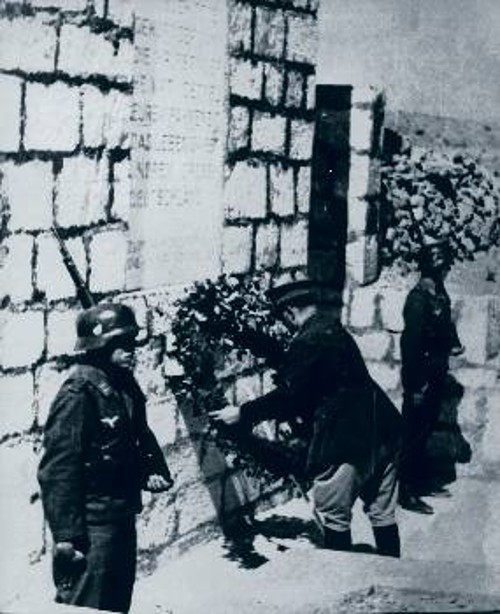 Στο μνημείο του Γερμανού άγνωστου στρατιώτη στην Κρήτη προσέρχεται ο πρώτος κατοχικός πρωθυπουργός Γ. Τσολάκογλου και καταθέτει στεφάνι. Τιμάει τους εισβολείς της ελληνικής Μεγαλονήσου ενώ δεν υπάρχει ακόμα τότε - το '42 - ηρώο των πεσόντων Κρητών, των αγωνιστών που στη «Μάχη της Κρήτης» εξουδετέρωσαν πέντε χιλιάδες αλεξιπτωτιστές, το πιο επίλεκτο σώμα της Βέρμαχτ