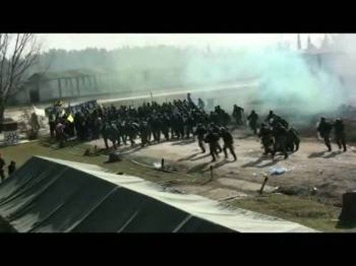Στιγμιότυπο από την άσκηση. Στρατός επιτίθεται κατά «διαδηλωτών» που κρατάνε πανό που γράφει PEACE (ειρήνη). Ακολουθούν στη συνέχεια τεθωρακισμένα που εκκαθαρίζουν την περιοχή!