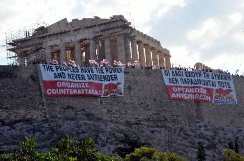 Τα συνθήματα στα πανό του ΠΑΜΕ στην Ακρόπολη εκπέμπουν το μήνυμα του αναγκαίου ξεσηκωμού, για να σαρώσουν οι λαοί τα μονοπώλια και την εξουσία τους