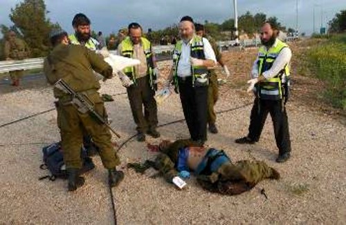 Ισραηλίτες στρατιώτες και «ορθόδοξοι εθελοντές» πάνω από το πτώμα ενός Παλαιστίνιου, που μόλις έχουν εκτελέσει