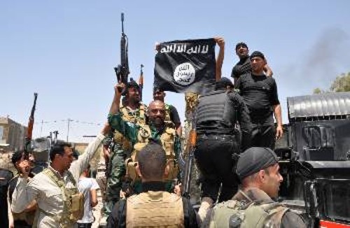 Ιρακινοί στρατιώτες κρατούν στα χέρια ως τρόπαιο τη μαύρη σημαία ισλαμιστών από περιοχή που ανακατέλαβαν το Σάββατο έξω από την Μπακούμπα