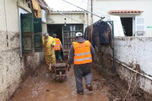 Εργαζόμενοι μαζί με τους πληγέντες καθαρίζουν τη λάσπη στα σπίτια