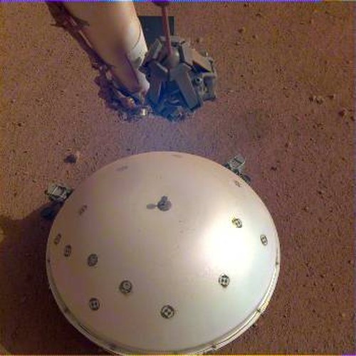 Ο ρομποτικός βραχίονας του «Mars InSight» μόλις έχει αποθέσει στο έδαφος του Αρη τον σεισμογράφο SEIS, που καλύπτεται από μια κυρτή ασπίδα προστασίας από τις θερμοκρασιακές μεταβολές και τον άνεμο