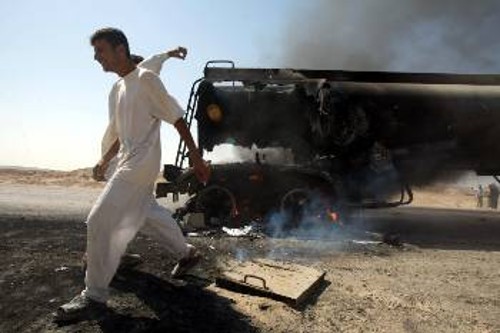 Ιρακινός διέρχεται δίπλα από φλεγόμενο όχημα των κατοχικών δυνάμεων μετά από επίθεση της ιρακινής αντίστασης