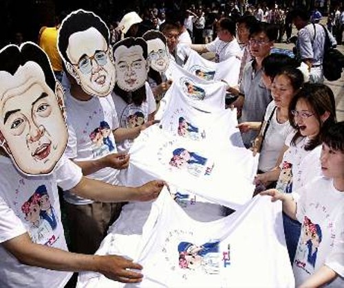 Ενόψει της συνάντησης κορυφής, εργάτες ενός εργοστασίου πωλούν φανελάκια φορώντας μάσκες με τα πρόσωπα των δύο ηγετών της Κορεατικής Χερσονήσου