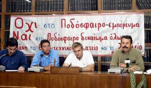 Στο προεδρείο της ημερίδας, διακρίνονται οι Γερ. Αραβανής, υπεύθυνος Αθλητισμού της ΚΕ του ΚΚΕ, ο Δ. Σαλπέας, μέλος του ΔΣ της ΕΠΣΠ, ο Δ. Κυζίλης, υπεύθυνος Αθλητισμού της ΚΟΠ και ο Δ. Μουρίκης, πρώτος αντιπρόεδρος της ΕΠΣΠ