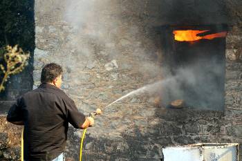 Με λάστιχο στα χέρια προσπαθούν οι κάτοικοι να σβήσουν τις φλόγες