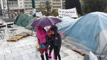 Παιδιά - προσφυγόπουλα προσπαθούν να προστατευτούν από τη βροχή