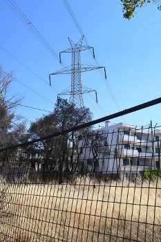 Πυλώνες υπερύψηλης τάσης πάνω από οικισμούς και τα χόρτα στο ένα μέτρο
