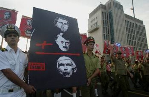 Από την πρόσφατη μεγάλη διαδήλωση, εύλογο το πλακάτ των διαδηλωτών, που διασυνδέει τον φασίστα εγκληματία Καρίλες με τον Μπους