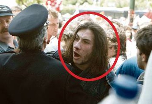 Πρωτομαγιά 2002. Ο ασφαλίτης Χρ. Γιαννακούλης, οπλισμένος, εφοδιασμένος με ταυτότητα σπουδαστή των ΤΕΙ και με ειδικά «επιμελημένη κόμη», ώστε να περνά απαρατήρητος, τη στιγμή που ο ίδιος και το όπλο του παραδίδονται από τους διαδηλωτές στους ανωτέρους του...
