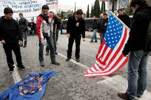 Εξω από την αμερικάνικη πρεσβεία, οι διαδηλωτές καίνε τις σημαίες των ΗΠΑ και ΕΕ: «ΝΑΤΟ και Βρυξέλλες φονιάδες των λαών κάτω η νέα τάξη των ιμπεριαλιστών», διατρανώνουν