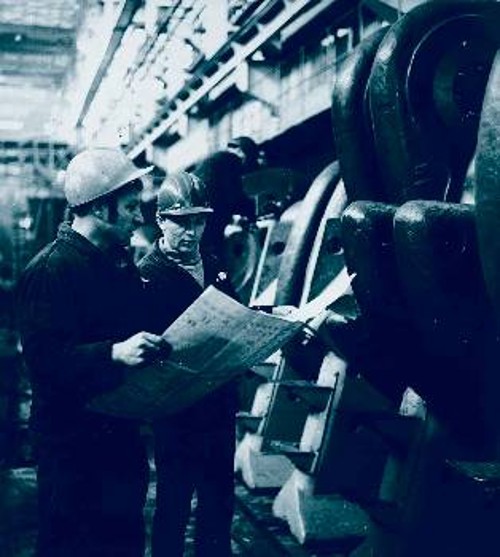 Επιχείρηση παραγωγής πετρελαιοκίνητων μηχανών για πλοία στο Μπριάνσκ της ΕΣΣΔ. Ο συναρμολογητής και ο μηχανικός κατά τη διάρκεια συναρμολόγησης ενός στροφαλοφόρου άξονα, μία από τις πιο σύνθετες διαδικασίες της κατασκευής μιας πετρελαιοκίνητης μηχανής 21.000 ίππων, με τη συνδρομή των τελευταίων τεχνολογικών μεθόδων (1976)