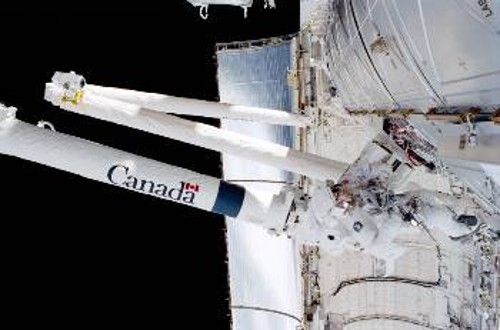 Ο καναδικής κατασκευής βραχίονας του Διεθνούς Διαστημικού Σταθμού κατά τη φάση προσαρμογής του, στα τέλη Απρίλη 2001. Στα δεξιά διακρίνεται ο αστροναύτης Σκοτ Παραζίνσκι