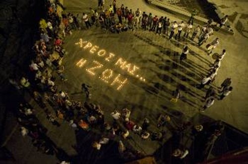 Το μήνυμα των μελών της «Παρέμβασης» γραμμένο με κεριά στην πλατεία Ομονοίας και γύρω οι νέοι του προγράμματος με τα κρουστά που φτιάχνουν οι ίδιοι