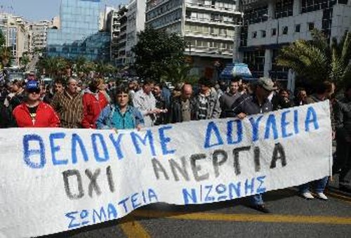 Οι άνεργοι εργάτες με το πανό τους διαδηλώνουν λίγο πριν από την επίθεση των δυνάμεων καταστολής