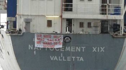 Το εγκαταλειμμένο πλοίο στην Ελευσίνα. Το πανό που έχουν σηκώσει γράφει: «Χρειαζόμαστε βοήθεια, χρειαζόμαστε μισθούς. Θέλουμε να πάμε σπίτια μας»