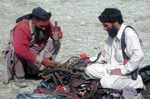 Ενας ένοπλος Πακιστανός συμπληρώνει τον οπλισμό του από κάποιον υπαίθριο πωλητή όπλων στην Πεσαβάρ, λίγο πριν αναχωρήσει για το Αφγανιστάν