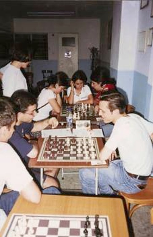 Ο νικητής των κλειστών τουρνουά του «Ικαρος», Αλεξ. Κωστούρος (δεύτερος αριστερά), στο ΣΟ Αμπελοκήπων. Στο βάθος σκακίστριες κάνουν ανάλυση παρτίδας
