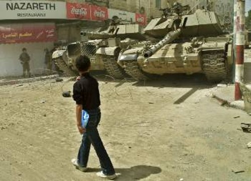 Νεαρός Παλαιστίνιος περνάει μπροστά από τα τανκς