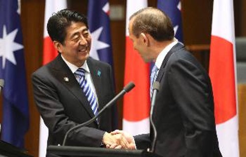 Τα χαμόγελα του πρωθυπουργού της Ιαπωνίας, αριστερά στη φωτογραφία, σε συνάντησή του με τον πρωθυπουργό της Αυστραλίας τον Ιούλη του 2014, τώρα έχουν παγώσει από την επιστροφή της οικονομίας σε κρίση
