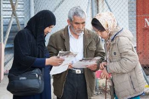 Πρόσφυγες διαβάζουν την ανακοίνωση του ΚΚΕ, μεταφρασμένη στη γλώσσα τους