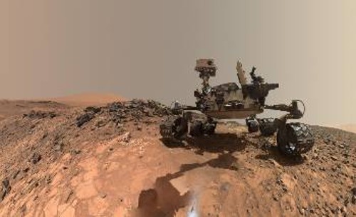 Πορτρέτο του «Curiosity» από την κάμερα στον βραχίονά του, μπροστά ακριβώς στο σημείο (διακρίνεται κάτω στο κέντρο) όπου χρησιμοποίησε το τρυπάνι του για να συλλέξει το δείγμα με τις οργανικές ουσίες