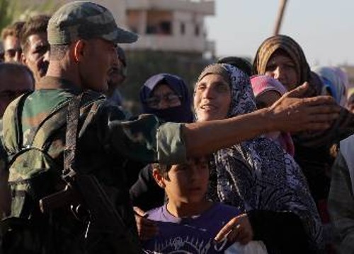 Σύρος στρατιώτης στην ανακατειλημμένη πόλη Ραστάν, όπου ο πληθυσμός είχε μείνει χωρίς τα βασικά αγαθά