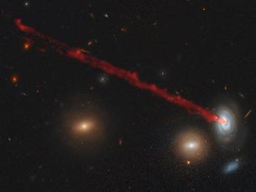 Κάτω δεξιά ο γαλαξίας D100 και η ουρά υδρογόνου και σκόνης που αφήνει πίσω του καθώς βυθίζεται στο γαλαξιακό σμήνος της Κόμης. Αριστερά και λίγο πιο κάτω απ' αυτόν, ο πρώην σπειροειδής γαλαξίας D99, που έχασε όλο το διάχυτο υδρογόνο του πριν από 500 εκατομμύρια έως 1,5 δισεκατομμύριο χρόνια. Τώρα μοιάζει με ελλειπτικό γαλαξία και εκπέμπει ένα κοκκινωπό χρώμα, καθώς περιέχει συγκριτικά περισσότερα γερασμένα άστρα που έχουν μεταβληθεί σε ερυθρούς γίγαντες