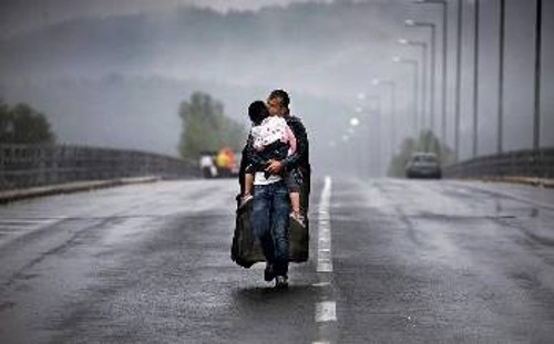 Από τις πλέον χαρακτηριστικές φωτογραφίες του Γ. Μπεχράκη. Ενας Σύρος πρόσφυγας αγκαλιά με το παιδί του, κοντά στην Ειδομένη...