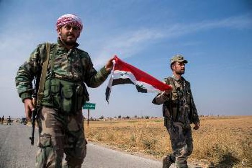 Σύροι στρατιώτες με τη σημαία της χώρας τους στα χέρια ενώ καταλαμβάνουν θέσεις σε περιοχές της Συρίας που βρίσκονταν χρόνια υπό τον έλεγχο Κούρδων μαχητών