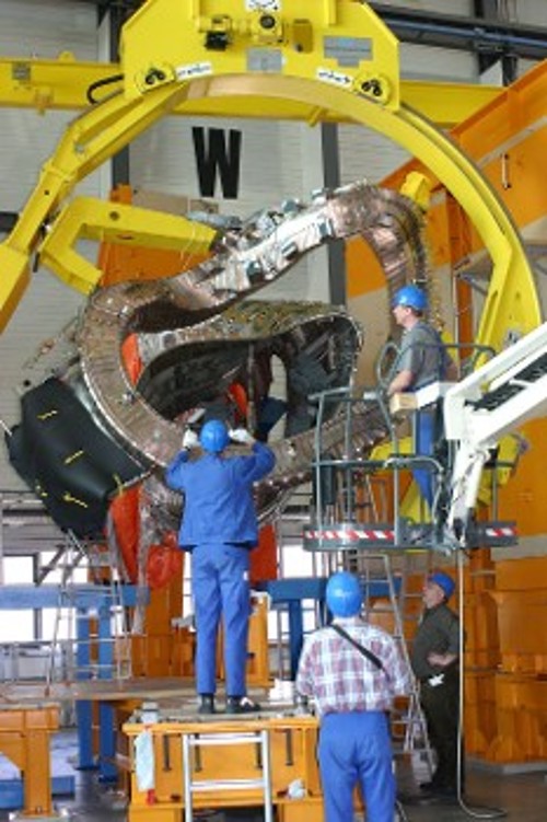 Εργάτες με τη βοήθεια γερανών συναρμολογούν τους παράξενου και δύσκολα κατασκευάσιμου σχήματος μαγνήτες των αντιδραστήρων τύπου stellarator