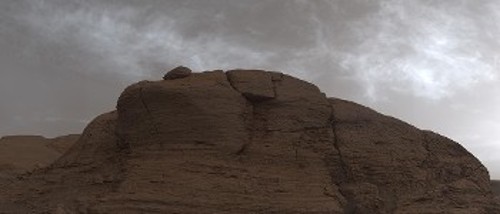 Τα σύννεφα στην ατμόσφαιρα του Αρη, όπως φωτογραφήθηκαν από το «Curiosity», στον ουρανό πάνω από έναν μεγάλο βράχο. Η χρωματική επεξεργασία έγινε ώστε να αποδοθούν τα χρώματα όπως θα φαίνονταν στο ανθρώπινο μάτι