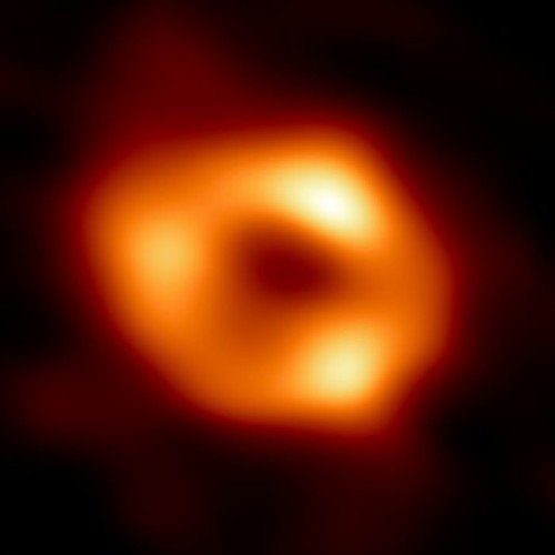 Η φωτογραφία της μαύρης τρύπας Τοξότης Α* στο κέντρο του Γαλαξία. Η «σκιά» της μαύρης τρύπας είναι η σκοτεινή περιοχή στο κέντρο. Στην πραγματικότητα έχει σφαιρικό σχήμα, αλλά η φωτεινότητα των τριών συγκεντρώσεων ύλης γύρω της και διάφορες άλλες παραμορφώσεις, σχετιζόμενες με τη διαδικασία παρατήρησης και επεξεργασίας των δεδομένων, την κάνουν να φαίνεται τριγωνική. Ο χρωματισμός είναι τεχνητός για να αναδεικνύεται καλύτερα η διαφορά λαμπρότητας των επιμέρους περιοχών