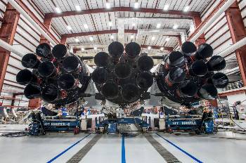 Οψη από κάτω, του συναρμολογημένου «Falcon Heavy». Σε πρώτο πλάνο τα 27 ακροφύσια των ισάριθμων κινητήρων των 3 πρώτων σταδίων των πυραύλων «Falcon 9», που αποτελούν από κοινού το πρώτο στάδιό του. Τα σημάδια στα ακροφύσια είναι πιο έντονα στους επαναχρησιμοποιημένους βοηθητικούς πυραύλους, αλλά υπάρχουν και στον κεντρικό, καθώς η «SpaceX» δοκιμάζει κάθε κινητήρα σε πλήρη ώθηση επί 3 λεπτά