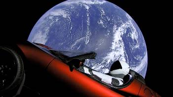 Αποψη της Γης από κάμερα στο πλευρό του χώρου φορτίου του «Falcon Heavy», με το αυτοκίνητο του Μασκ σε πρώτο πλάνο. Στη θέση του οδηγού ένας «φουσκωτός» αστροναύτης, μια κενή διαστημική στολή, σχεδίασης της «SpaceX»
