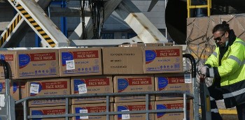 Εργαζόμενος στο αεροδρόμιο μεταφέρει φορτίο με μάσκες που πρόσφεραν «χορηγοί» για την αντιμετώπιση της πανδημίας