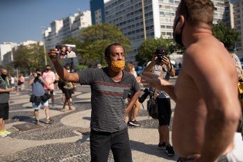 Ο Μάρσιο Αντόνιο ντο Νασιμιέντο δείχνει τη φωτογραφία του 25χρονου γιου του Χιούγκο, που πέθανε από COVID-19, σε έναν άλλο Βραζιλιάνο, ο οποίος υποστηρίζει ότι η πανδημία είναι μια απάτη, σε μια χώρα που ήδη μετράει περισσότερους από 100.000 νεκρούς απ' αυτήν
